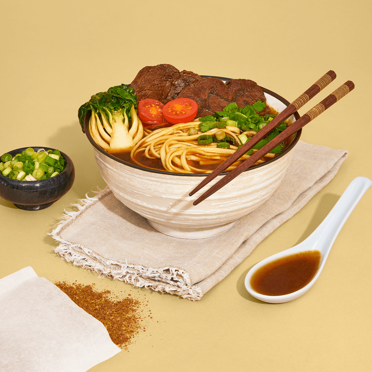 A bowl of Taiwanese beef noodle soup with bok choy, noodles, and chopsticks