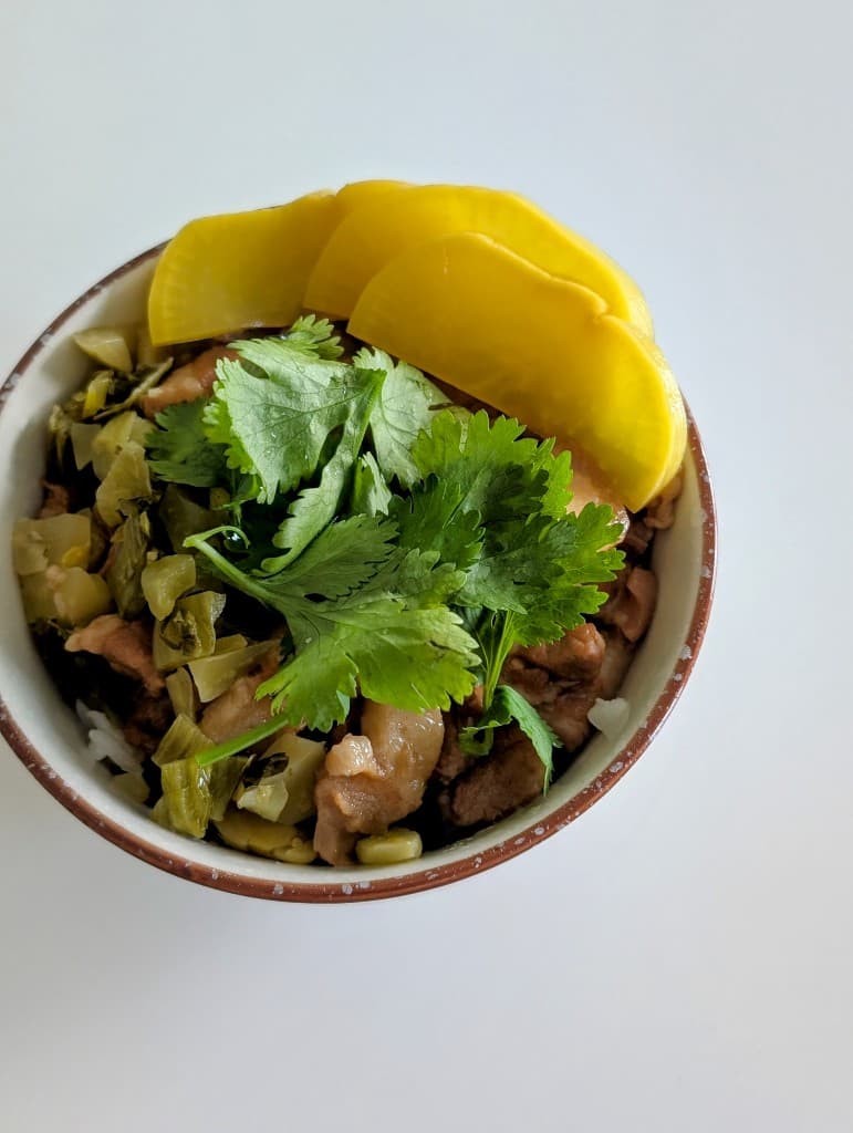 Braised pork belly over rice with cilantro and pickled radish